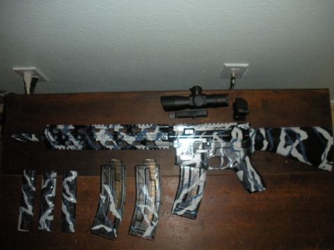 1996 Ford Bronco - A rifle with a distinctive camouflage wrap, complete with a scope and extra magazines, is displayed on a wooden surface.