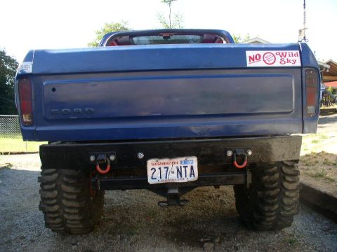 1979 Ford Bronco - Rear view of a blue pickup truck oversized tires and a "NO Wild Sky" sticker on the tailgate.
