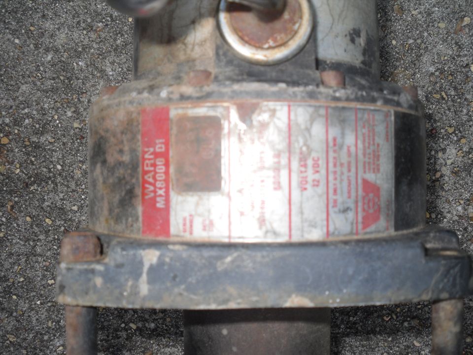 Close-up of a Warn MX8000 D1 winch motor with a 12 VDC label