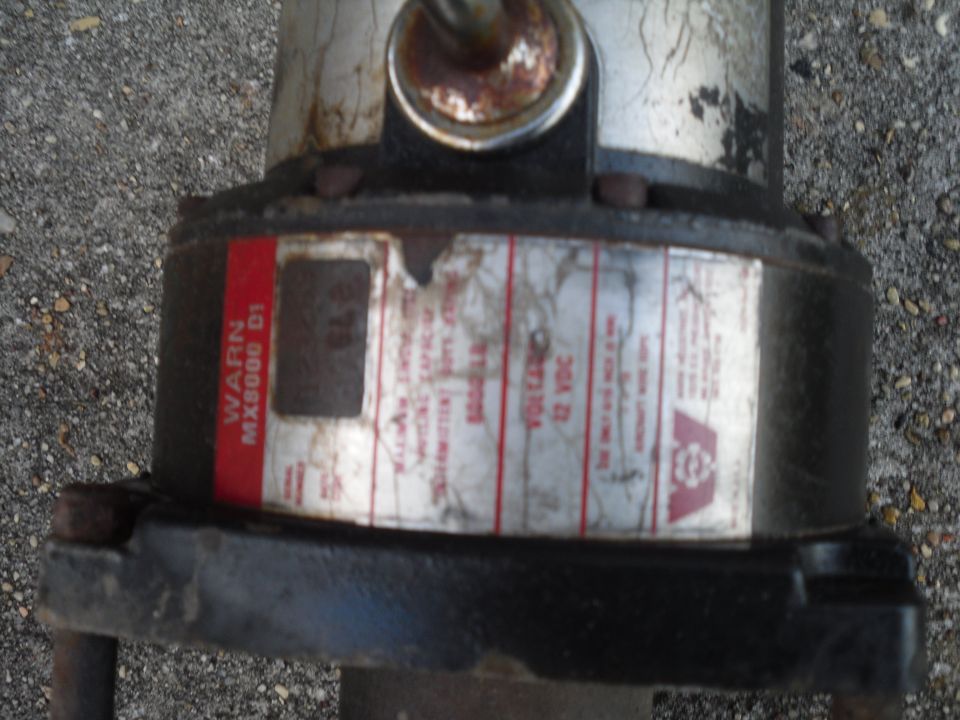 Worn WARN MX8000 D1 winch with a 12 VDC label