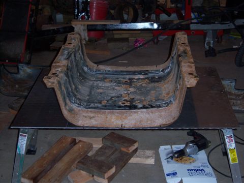 1996 Ford Bronco - A heavily rusted metal component is displayed on a workbench, possibly for restoration.