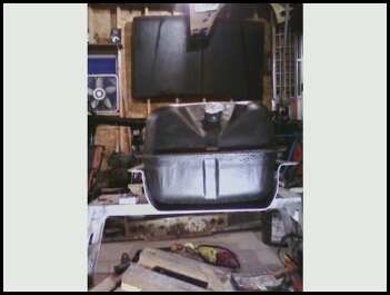 1996 Ford Bronco - A black plastic gas tank with metal straps is shown, possibly for a truck or SUV, in a workshop setting.