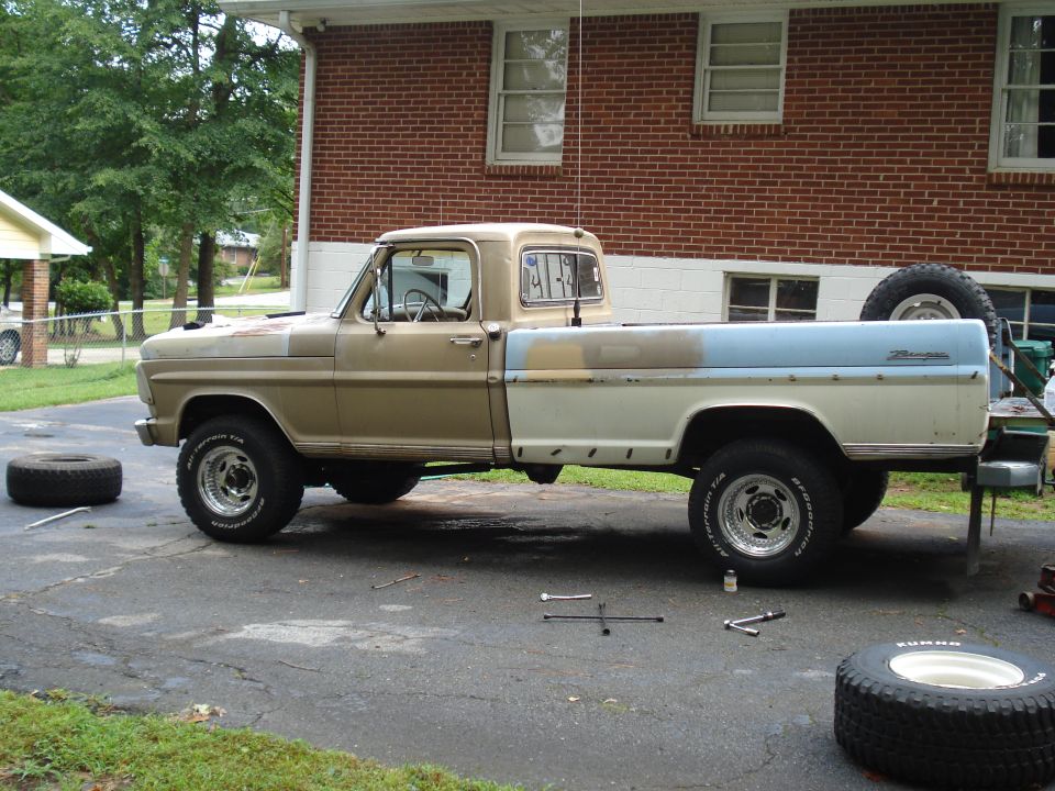 1967 Ford F-250 pickup truck parked in driveway with spare tires nearby