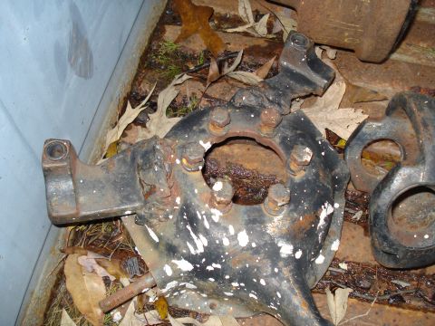 1967 Ford F-250 - A close-up view of a heavily rusted vehicle suspension component lying on the ground.