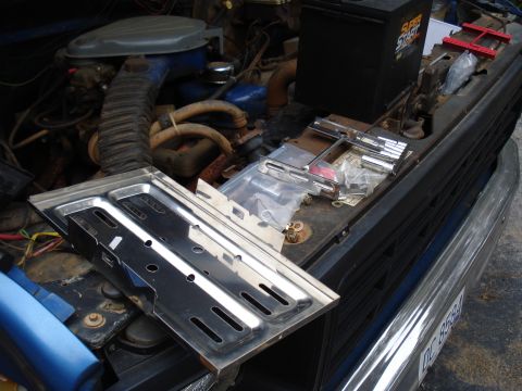 1967 Ford F-250 - Engine bay of a truck, showing the battery and various new parts ready for installation. A license plate is partially visible.
