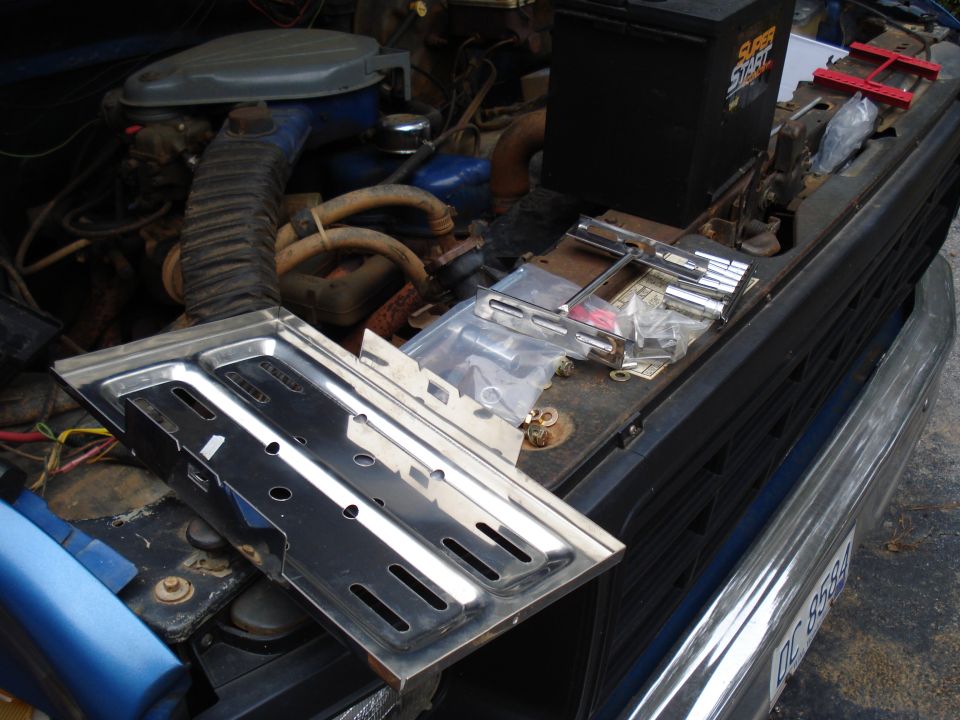 Engine bay with battery and new parts laid out. License plate DC 8584 visible