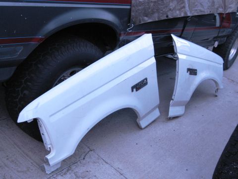 1986 Ford Bronco - Two detached fenders from a Ford F-250 truck are shown, with another vehicle partially visible behind them.