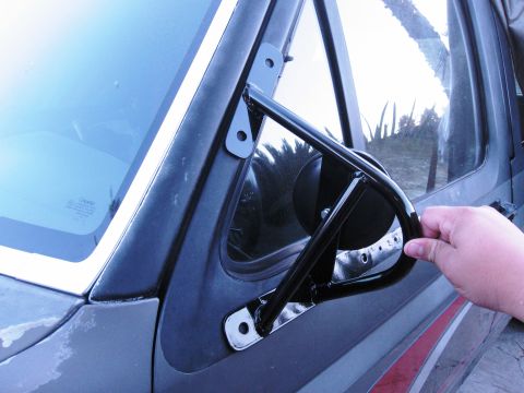 1986 Ford Bronco - Close-up of an aftermarket side mirror assembly attached to a vehicle's door frame.