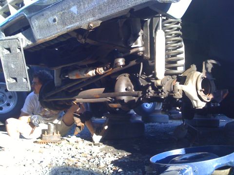 1989 Ford Bronco - A mechanic works on the suspension and axle of a vehicle that appears to be undergoing maintenance or repair.