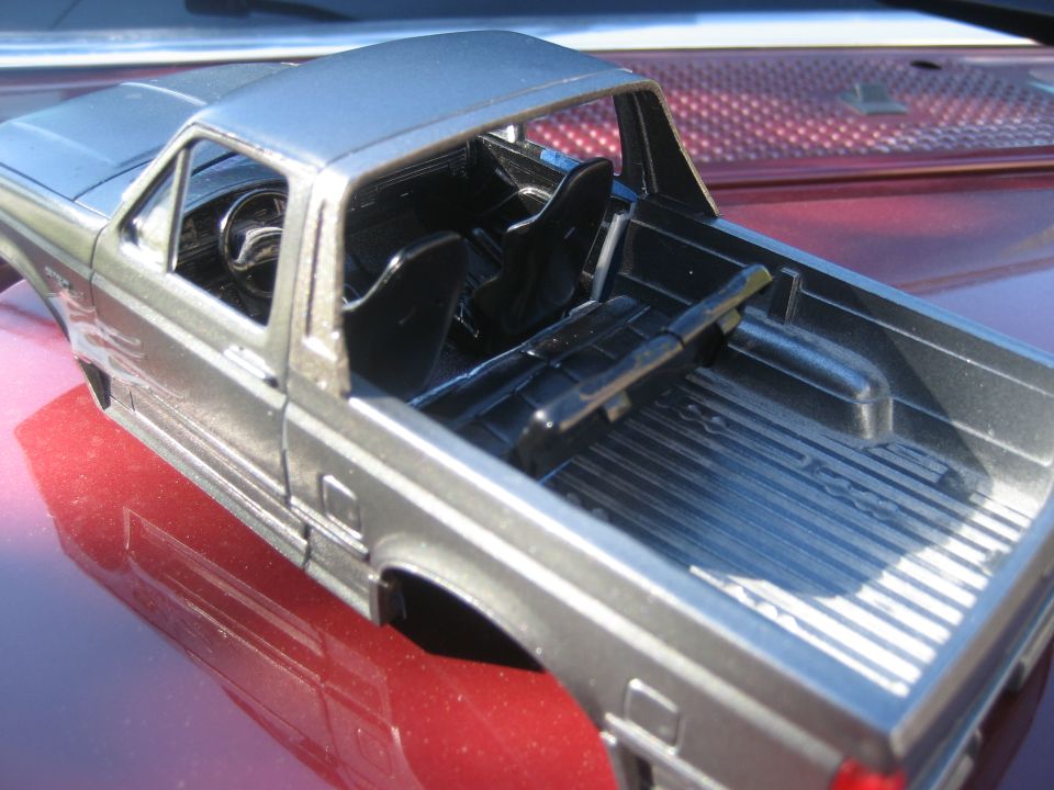 Silver model truck interior with bucket seats and a bed
