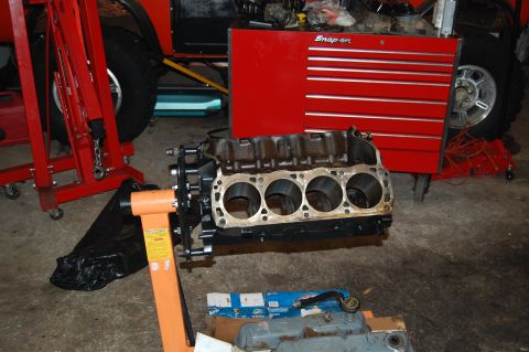 1994 Ford Bronco - An engine block is on a stand in a garage, next to a red tool chest and a vehicle.