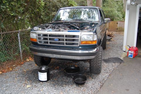 1994 Ford Bronco - Front view of a 1994 Ford Bronco undergoing maintenance, with oil drain pans visible.