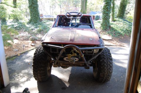 1994 Ford Bronco - This heavily modified off-road vehicle features a prominent roll cage and oversized tires, with a Toyota badge visible on the front.