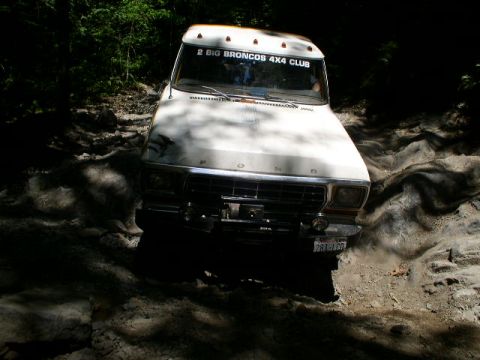 1979 Ford Bronco - A white Ford Bronco navigates a challenging, rocky off-road path.