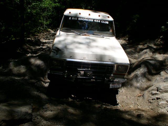 White 1978 Ford Bronco on a rough, muddy trail, front view
