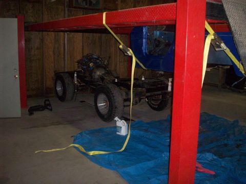 1978 Jeep CJ5 - Jeep CJ5 chassis and engine assembly suspended on a red lift in a garage.