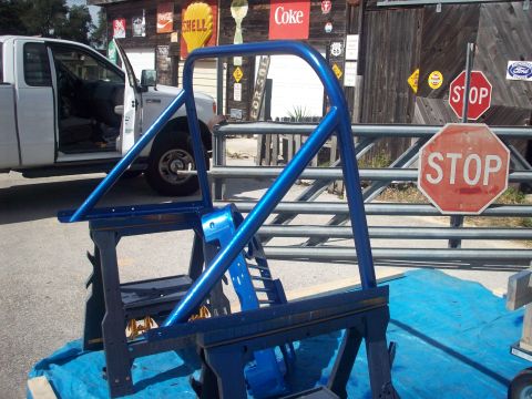 1978 Jeep CJ5 - A blue roll cage sits on sawhorses in front of a building with vintage signs and a pickup truck.