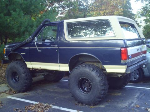 1990 Ford Bronco - This lifted 1990 Ford Bronco features a snorkel and large off-road tires, suggesting it's modified for terrain.