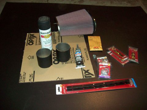 1985 Ford Bronco - Collection of automotive parts and hardware, including an air filter and spray paint, laid out on a surface.