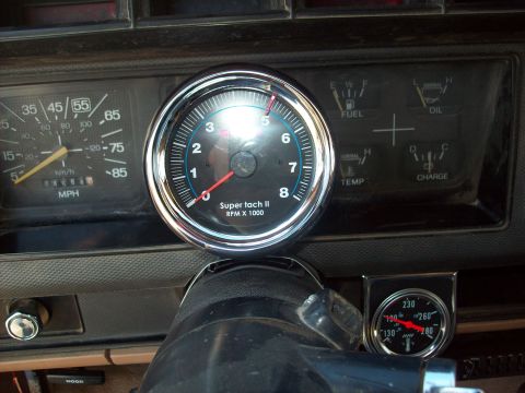 1985 Ford Bronco - Close-up of a vehicle's dashboard, showing various gauges and an aftermarket tachometer.
