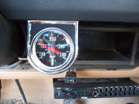 1985 Ford Bronco - Close-up of an aftermarket temperature gauge installed in a vehicle's dashboard.