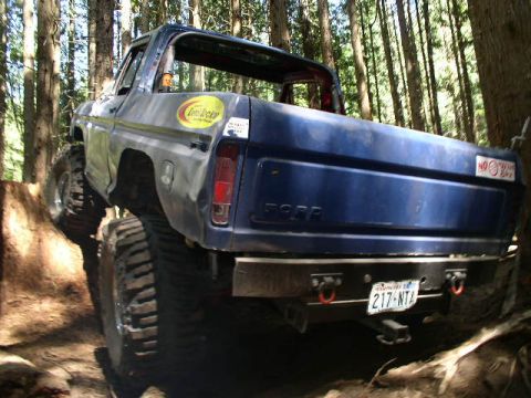 1979 Ford Bronco - This modified truck, likely a 1978 Ford Bronco, navigates a wooded trail with its rear end angled towards the camera.