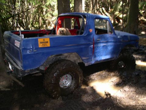 1979 Ford Bronco - This 1979 Ford Bronco navigates a muddy trail, its large tires digging into the mire.