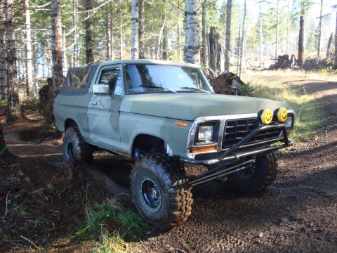 1978 Ford Bronco - Modified 1978 Ford Bronco navigating a wooded trail with large tires and a custom bumper.