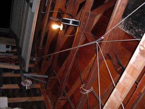 1991 Ford Bronco - The interior of a garage ceiling shows the complex mechanism of a garage door opener, including a light bulb and various cables.
