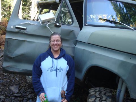 1978 Ford Bronco - A woman smiles next to a heavily modified 1978 Ford Bronco with significant body damage.