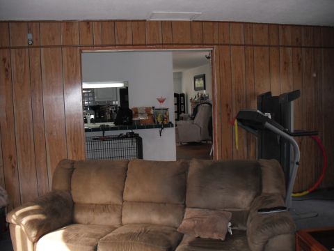 1991 Ford Bronco - This image depicts an indoor scene a large brown couch in the foreground and a treadmill to the right, set against wood-paneled walls.