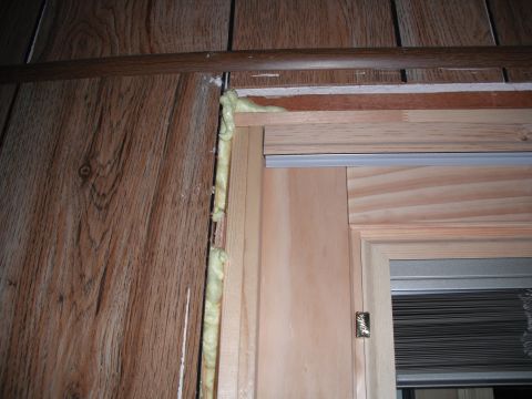 1991 Ford Bronco - Expanding foam insulation is visible around the door jamb, contrasting with the wood paneling.