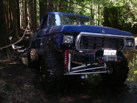 1979 Ford Bronco - This modified SUV navigates a wet, wooded trail with its front end angled towards the viewer.