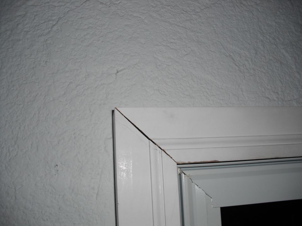 Close-up of a white door frame with textured wall in background