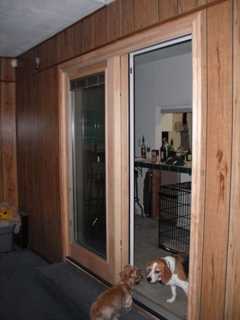 1991 Ford Bronco - Two dogs interact near a sliding glass door in a room with wood-paneled walls.