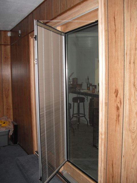 1991 Ford Bronco - Interior view of a room with wood paneling and an open screen door leading to a bar area.