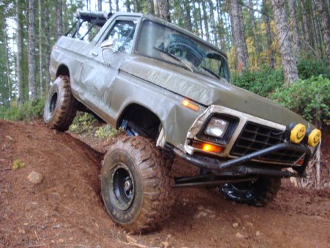 1978 Ford Bronco - A modified 1978 Ford Bronco navigates a steep, muddy trail in a forest setting.