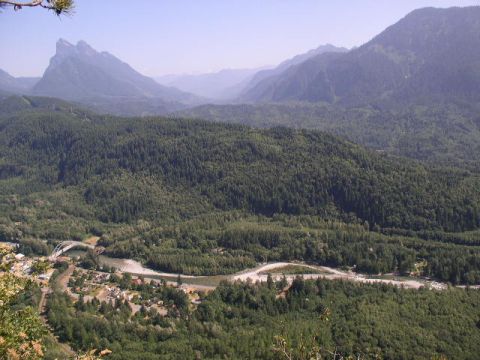 1979 Ford Bronco - A scenic view of a valley with a river, a small town, and a bridge, framed by forested mountains.