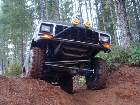 1978 Ford Bronco - This modified truck navigates a steep, muddy incline through a forest.