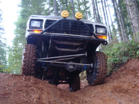 1978 Ford Bronco - A modified 1978 Ford Bronco navigates a steep, muddy incline in a forest.