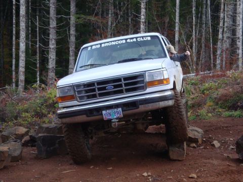1978 Ford Bronco - A white Ford Bronco navigates a rocky trail, its tires climbing over large stones.