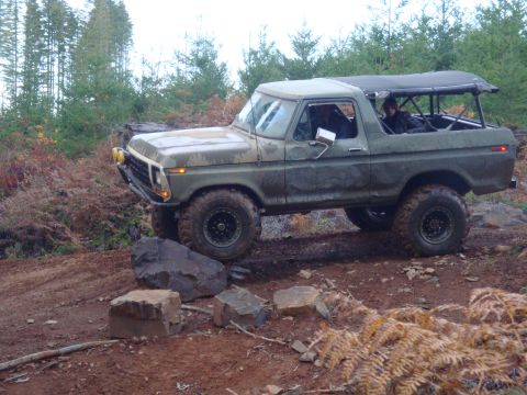 1978 Ford Bronco - A 1978 Ford Bronco navigates a rocky trail in a wooded area.