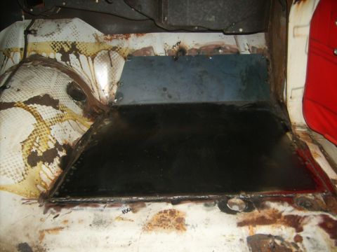 1963 Ford Galaxie - Close-up view of a vehicle's interior floor pan, showing rust and a newly welded metal patch.