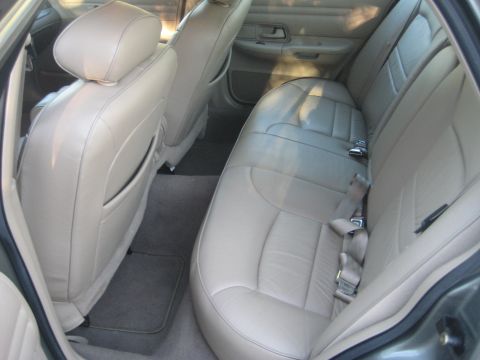 1999 Ford Crown Victoria - Rear interior view of a 1999 Ford Crown Victoria, showing tan leather seats and carpeting.