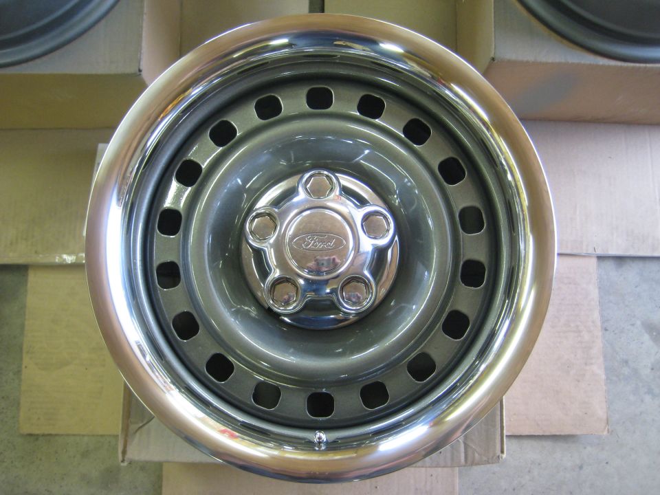 Gray Ford steel wheel with polished chrome lip and Ford center cap resting on cardboard boxes