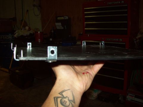 1985 Ford Bronco - A metal plate with brackets is held in a workshop, with a red Craftsman tool chest in the background.