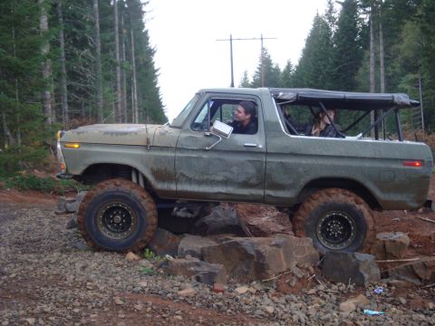 1978 Ford Bronco - A 1978 Ford Bronco navigates a rocky trail in a wooded area.