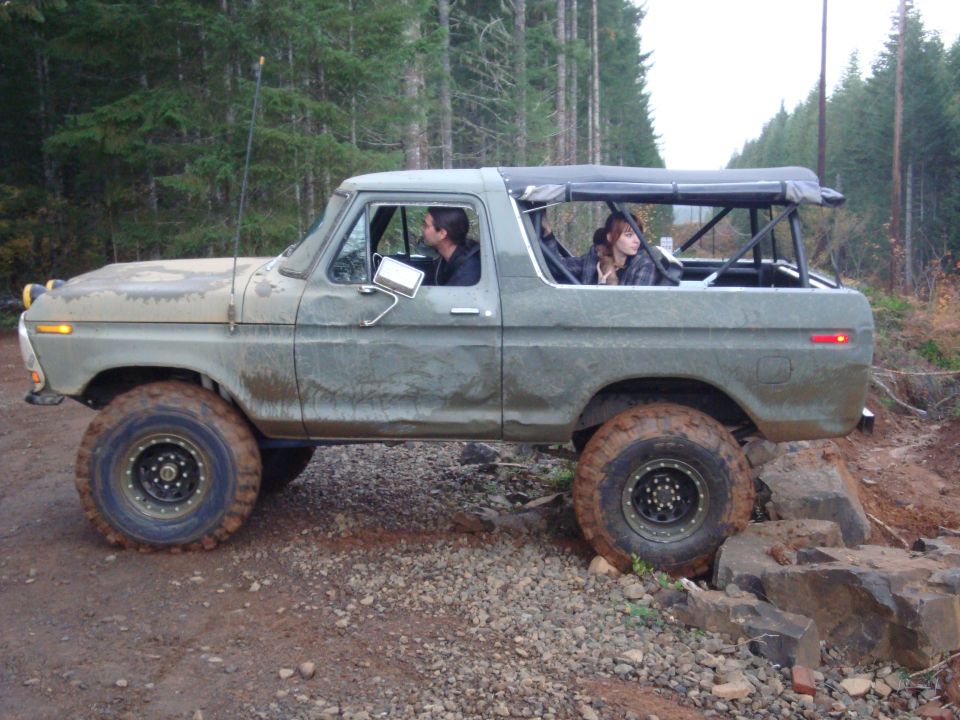 1978 Ford Bronco with soft top, driving over rocks on a dirt trail