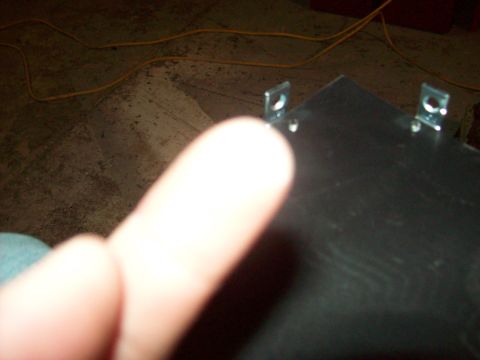 1985 Ford Bronco - A close-up view of a metal bracket with mounting holes, with a finger obscuring part of the image. The Supermotors.net logo is visible.