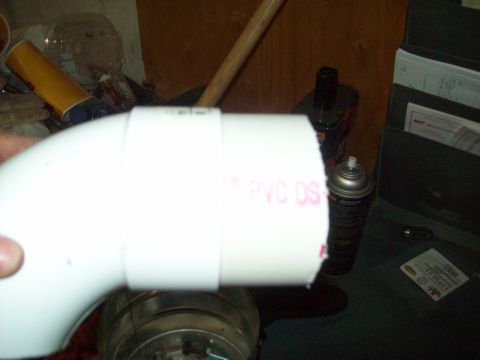 1985 Ford Bronco - A hand holds a white PVC pipe fitting in front of a cluttered background with a spray can.